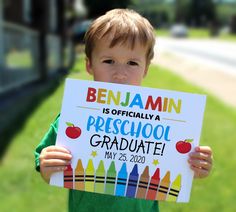 a young boy holding up a sign that says benjamin's first day of preschool