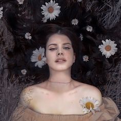 a painting of a woman laying down with daisies on her chest and hair blowing in the wind