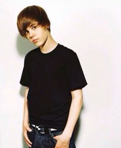 a young man standing in front of a white wall with his hands on his hips