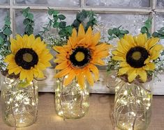 three mason jars with sunflowers and fairy lights