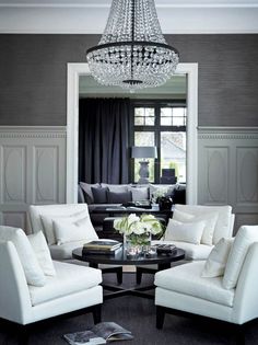 a living room filled with white furniture and a chandelier hanging from the ceiling