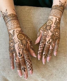 two hands with henna tattoos on them