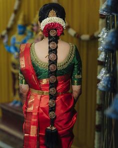 a woman in a red and green sari with long braids on her head