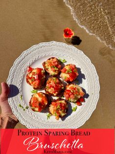 a white plate topped with food on top of a sandy beach next to the ocean