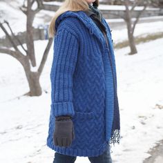 a woman walking in the snow wearing a blue coat