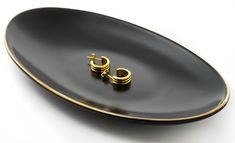 a black plate with two small gold hoop earrings on the side and a white background