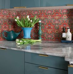 a blue vase with tulips sits on a marble countertop