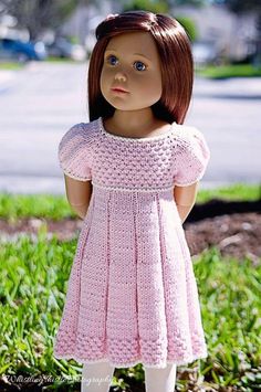 a doll is standing in the grass wearing a pink crochet dress and white tights