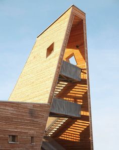 a tall wooden building with stairs leading up to it's second floor and the roof