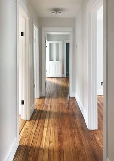 an empty hallway with white walls and wooden floors is seen in this image from the front door