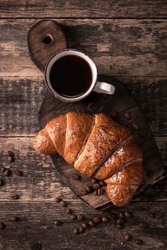 coffee and croissants on a wooden table with beans around them, top view