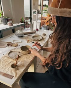 a woman sitting at a table with bowls and spoons