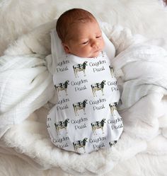 a baby wrapped in a blanket sleeping on top of a white blanket