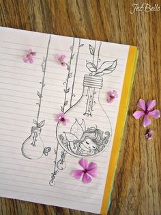 an open notebook with flowers on it and some writing paper next to the pages that have been drawn