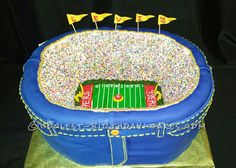 a cake that is shaped like a football field with flags on it and sprinkles