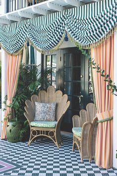 an outdoor patio with wicker furniture and striped awning