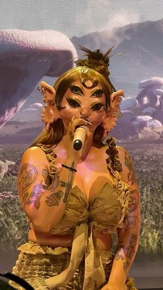 a woman with tattoos on her body and head is holding a microphone in front of a backdrop