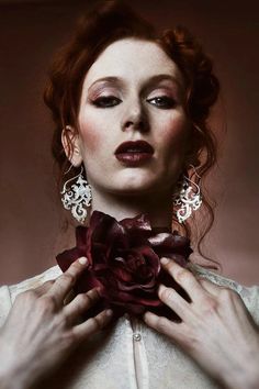 a woman with red hair holding a flower in her hands