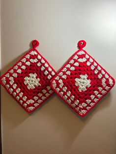 two red and white crocheted squares hanging on a wall