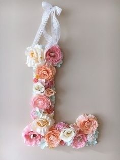 the letter j made out of flowers is hanging on a wall with a white ribbon