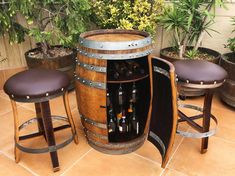 a wooden barrel with two stools next to it and some bottles in the back