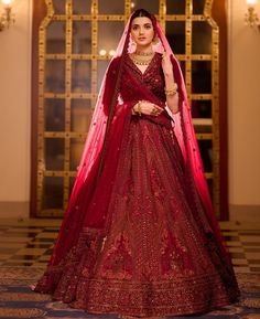 a woman in a red bridal gown standing with her hands on her hips and looking at the camera