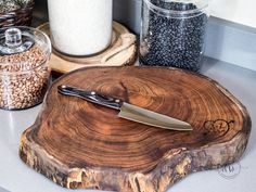 a wooden cutting board with a knife on it next to some spices and other items