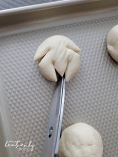 dough being cut into small balls with a pair of scissor on the side