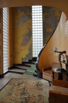 a spiral staircase in the middle of a room with yellow walls and rugs on the floor