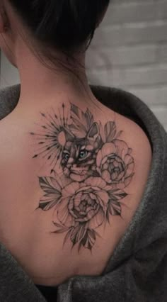 a woman's upper back tattoo with flowers and an owl in the center on her left shoulder