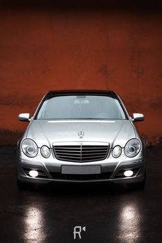 a silver car parked in front of a red wall