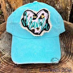 a blue hat with the word mama embroidered on it sitting on top of a tree stump