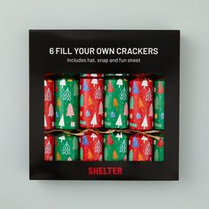 six christmas crackers in a black box with red, green and white trees on them