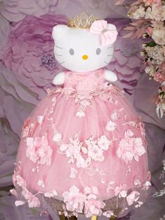 a hello kitty doll wearing a pink dress with flowers on the bottom and a gold crown on top