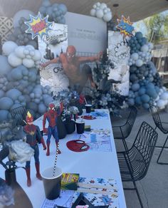 the table is set up for a spiderman themed birthday party with balloons and decorations