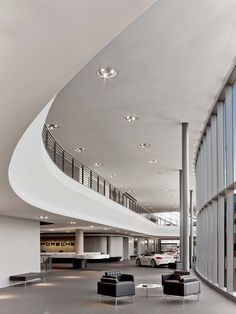 the interior of a modern building with high ceilings and large windows that overlook parking spaces