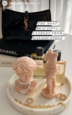 two small figurines sitting on top of a white tray next to perfume bottles