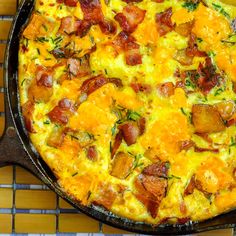 an omelet with bacon and cheese in a cast iron skillet on a tiled surface