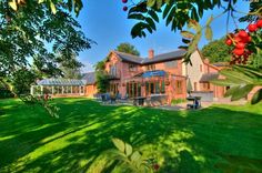 a large house sitting in the middle of a lush green field with lots of trees