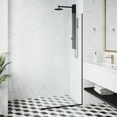 a bathroom with black and white tile flooring, gold trimming on the shower