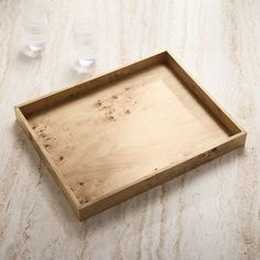 a wooden tray sitting on top of a counter next to two empty water glasses and an empty bottle