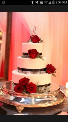 a three tiered wedding cake with red roses on the top and silver trimmings