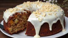 a bundt cake with white frosting and nuts on top is sitting on a plate