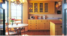 a kitchen with wooden floors and yellow cabinets, along with a dining room table set for four