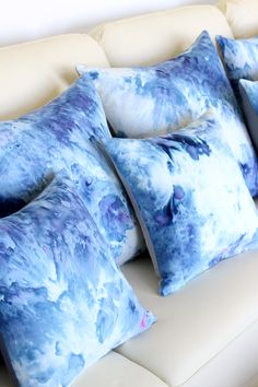 four blue pillows sitting on top of a white couch