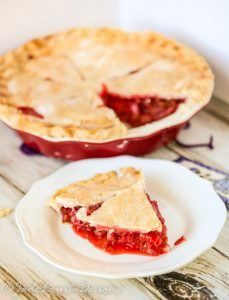 a piece of pie sitting on top of a white plate next to a red dish