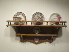 a shelf with plates and cups on top of it in front of a white wall