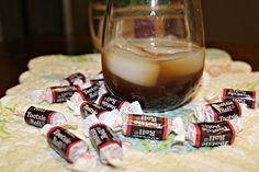 a glass filled with liquid sitting on top of a table next to small candy bars