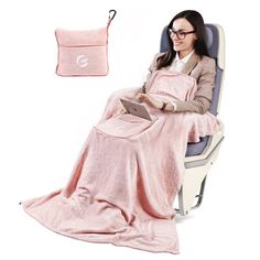 a woman sitting in a chair with a pink blanket on her lap and holding a laptop