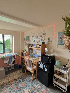 a room with a bed, desk and shelves filled with books on it next to a window